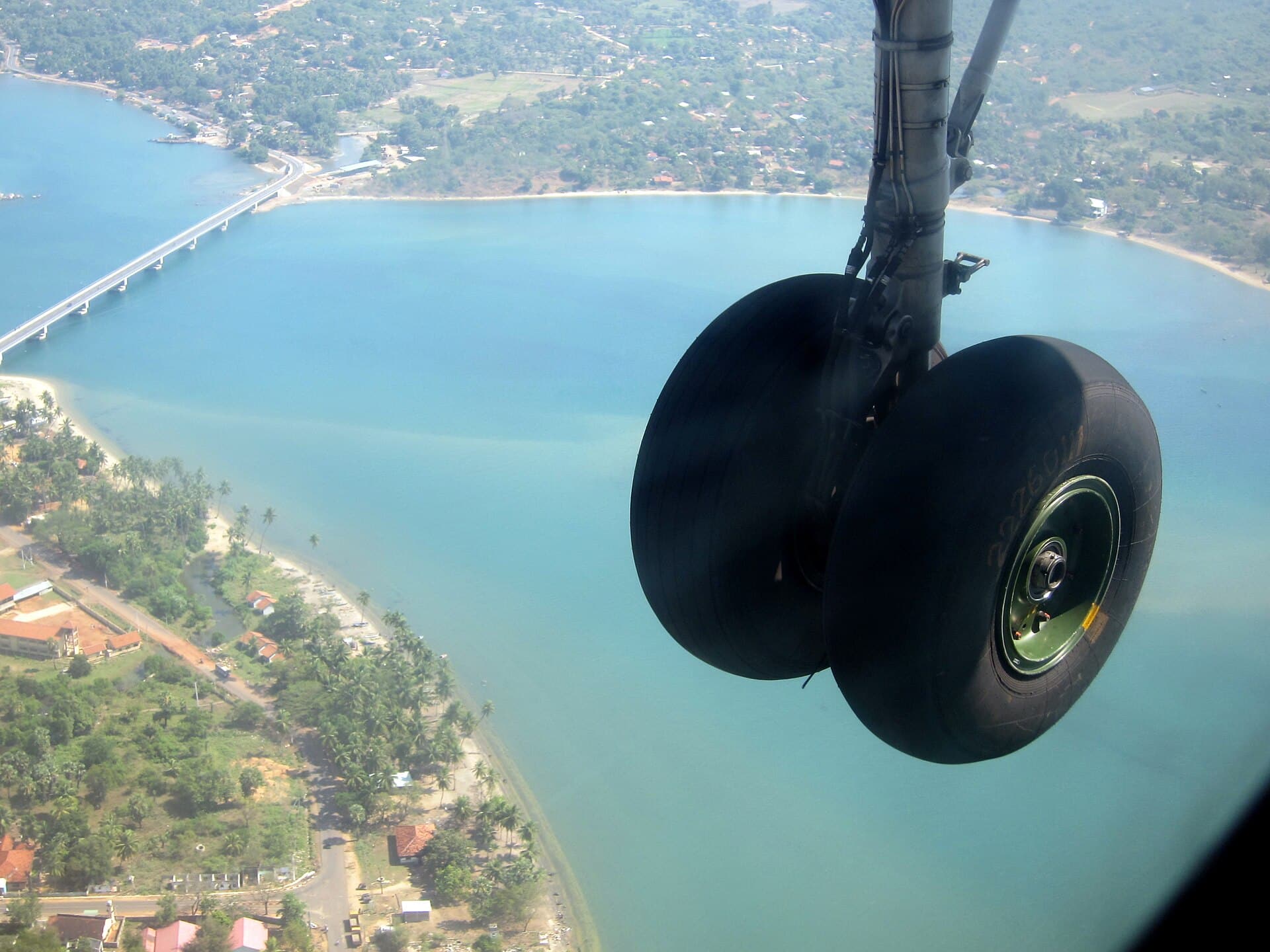 An aircraft's wheels coming down over the lagoon and the bridge at Kinniya